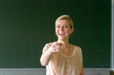 Okul öğretmeni, sınıfta tahtaya basıp parmağıyla işaret ederek seni işaret ediyor.