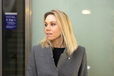 Omuz hizasında, sarışın, ilgi çekici bir yüz ifadesi olan ve dudaklarını ayıran bir kadın.