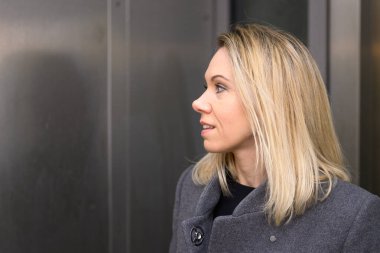 Çerçevenin soluna bakan uzun sarı saçlı çekici orta yaşlı bir kadının profil fotoğrafı.