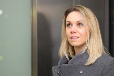 Omuz hizasında sarışın bir kadın. İlgi çekici bir ifadeyle yukarı bakıyor ve yakın mesafeden dudaklarını ayırıyor.