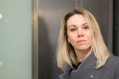 Kendine güveni tam, sarışın bir kadın yakın plan bir portrede tuhaf bir ifadeyle kameraya bakıyor.