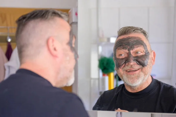 Mann Mit Modischem Kurzhaarschnitt Checkt Seine Kosmetische Gesichtsmaske Badezimmerspiegel — Stockfoto