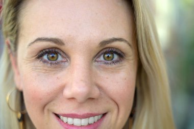Cropped close up portrait of the face of an attractive woman with long blond hair smiling at the camera