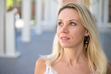 Thoughtful blond woman in a close up profile portrait looking off to the side with a pensive expression