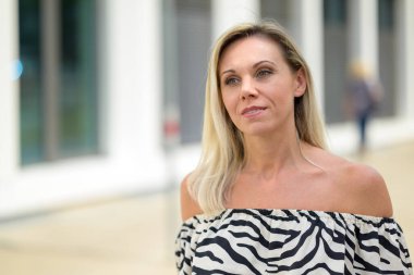 Attractive middle aged woman in an elegant black and white summer dress walking down a city street