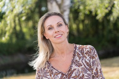 Kırsalda güzel, gülümseyen, olgun bir kadının portresi.