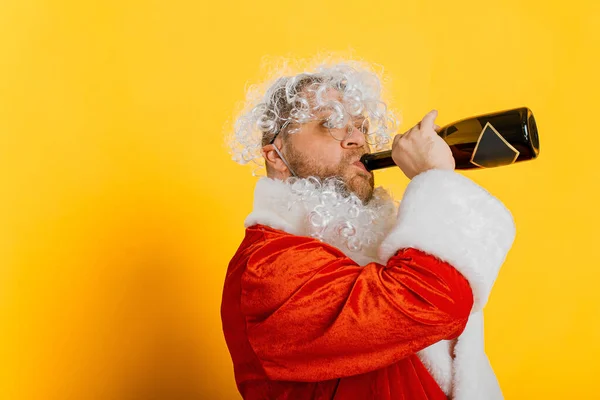 Drunk Unshaven Santa Drinks Champagne Neck Bottle Yellow Isolated Background — Stockfoto