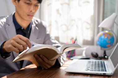 İşadamı masasında kitap okuyor.