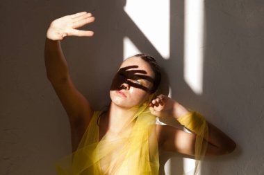 Sarı elbiseli, çilli, genç ve güzel bir kadın. Arka planda, öğleden sonra gölgeleri olan..