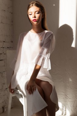 Güneş ışığında sandalyede zarif poz veren kadın.