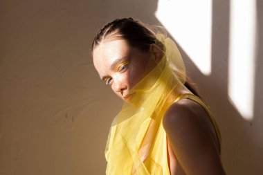 Sarı elbiseli, çilli, genç ve güzel bir kadın. Arka planda, öğleden sonra gölgeleri olan..