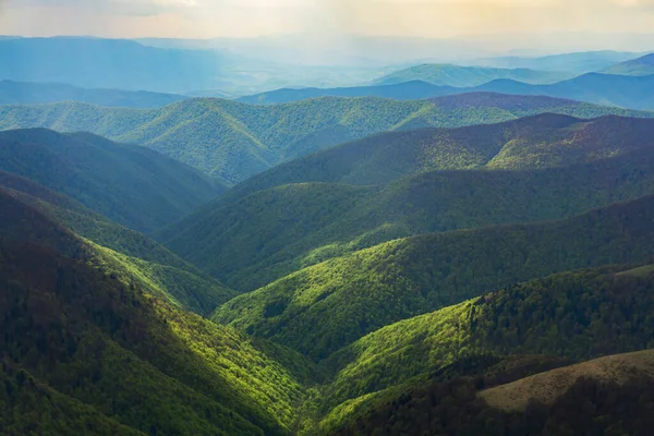 Güneş bulutlu gökyüzünün altında yeşil dağları aydınlattı.