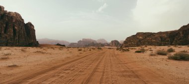 Wadi Rum çölü, Ürdün, Ay Vadisi. Turuncu kum, pus, bulutlar. Unesco Dünya Mirası Listesi'ne atılmıştır. Milli park açık hava manzarası. Offroad maceraları seyahat arka plan.