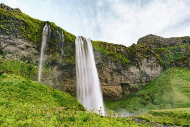 Seljalandfoss şelalesi Seljalandsa nehrinde. Yaz manzarası. İzlanda, Avrupa. Yatay arkaplan, kopyalama alanı.