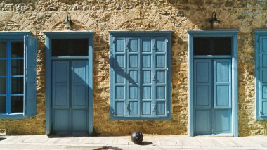 Blue wooden doors and windows shutters on yellow stone walls. Greece, Nafplion.