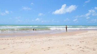 Recife, PE, Brezilya - 14 Ekim 2021: Boa viagem plajında yıkanır. İnsanlar güzel güneşli bir günde sahilde günün tadını çıkarıyorlar. Sağa doğru video hareketi.