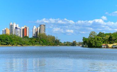 Igapo Gölü manzarası, Londrina - PR, Brezilya. Güzel şehir gölü, kıyıların etrafındaki ağaçlarla ve arka plandaki şehir binalarıyla, mavi gökyüzü gününde.