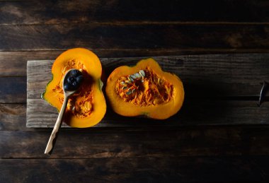 Tahta bir masanın üzerindeki kesikte portakal kabağı.