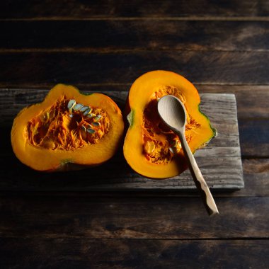 Tahta bir masanın üzerindeki kesikte portakal kabağı.