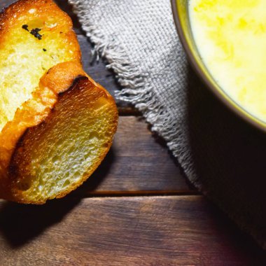 Tahta bir masada, kahverengi bir tabakta kabak çorbası püresi.