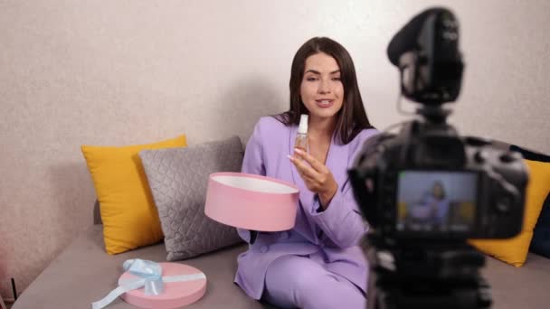 Leende söt ung kvinna influencer packa upp stora pappkartong, i soffan — Stockvideo