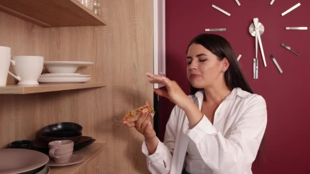 La mujer tiene buen apetito, vestida con una camisa blanca casual. Mujer hambrienta interior. — Vídeos de Stock