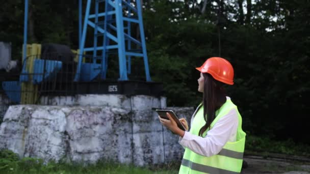 Kobieta inżynier trzyma tabletkę w rękach i dokonuje obliczeń dla produkcji oleju — Wideo stockowe