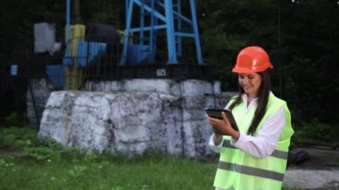 Kadın mühendis tableti elinde tutuyor ve petrol üretimi için hesaplamalar yapıyor.