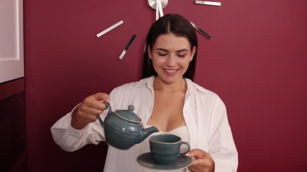 Mujer vertiendo té en la taza en el acogedor interior de la casa. carácter femenino beber caliente — Vídeos de Stock