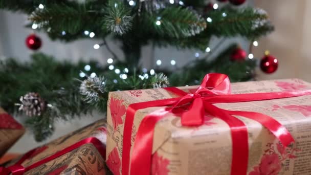 Gyönyörű karácsonyi ajándékdobozok a padlón a fenyőfa mellett a szobában. Karácsonyi dekorációk — Stock videók