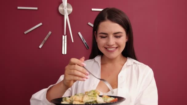 Joven mujer feliz comiendo ensalada saludable ingredientes frescos verdes en el interior. Hermosa. — Vídeo de stock