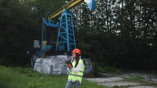 Kobieta inżynier trzyma tabletkę w rękach i dokonuje obliczeń dla produkcji oleju — Wideo stockowe