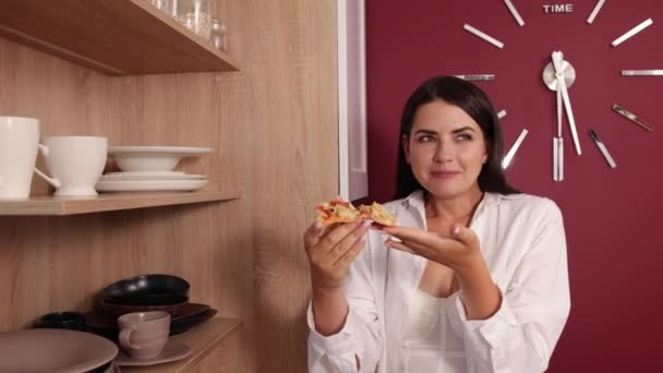 Ung amerikansk kvinna med svart hår äter skiva av läcker italiensk pizza — Stockvideo