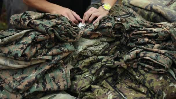 Las manos eligen uniformes militares de camuflaje para jugar paintball. Primer plano. — Vídeo de stock