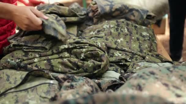 Hands choose camouflage military uniforms for playing paintball. Close-up. — Stock Video