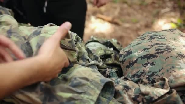 As mãos escolhem uniformes militares de camuflagem para jogar paintball. Close-up. — Vídeo de Stock