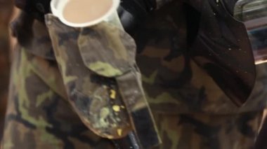 Erkek eli boya toplarını paintball silahlarının deposuna koyar.