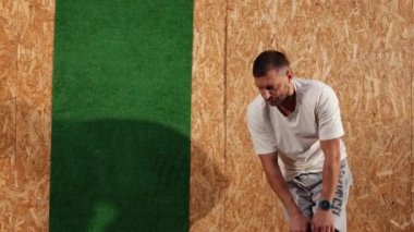 Eşofmanlı adam bağlarını esnetebilmek için bacağını dizinden tutuyor. Spor.