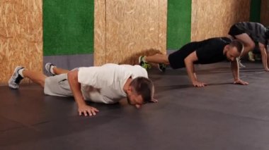 Güçlü formda sporcular tavan arası tarzı endüstriyel spor salonunda şınav çekiyorlar.