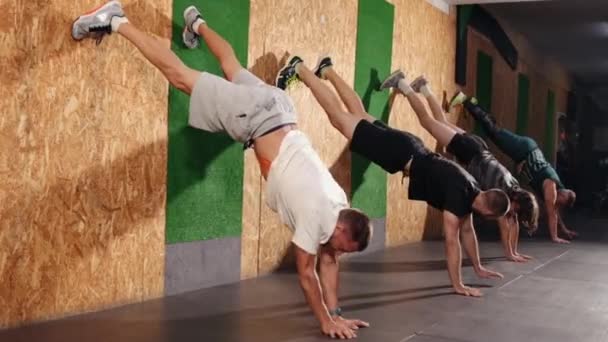 Pria fit muda melakukan latihan handstand di studio. Sekelompok atlet senam — Stok Video