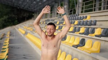 Genç güçlü kaslı üstsüz beyaz erkek sporcu burpee egzersizi yapıyor.