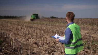 Çiftçi hasat işini kontrol ediyor. Hasat sırasında kurumuş ayçiçeği tarlası. Birleştir