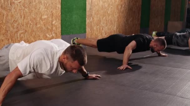 Sterke fit atletische mannen doen push-up oefeningen in een loft stijl industriële sportschool — Stockvideo