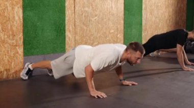 Güçlü formda sporcular tavan arası tarzı endüstriyel spor salonunda şınav çekiyorlar.