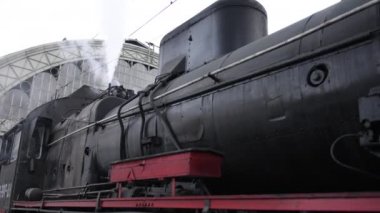 Retro buhar treni tren istasyonundan ayrılıyor. Mavi arabalı eski siyah buhar treni