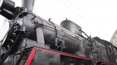 Retro buhar treni tren istasyonundan ayrılıyor. Mavi arabalı eski siyah buhar treni