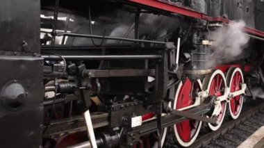 Retro buhar treni tren istasyonundan ayrılıyor. Mavi arabalı eski siyah buhar treni