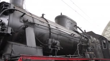 Retro buhar treni tren istasyonundan ayrılıyor. Mavi arabalı eski siyah buhar treni