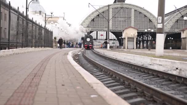 Ретро паровоз отходит от железнодорожной станции. Старый чёрный паровоз с синими машинами — стоковое видео