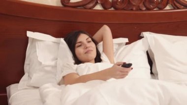 Evde kanepede uzanmış, uykulu hissediyorum, uzaktan kumandayı gösteriyorum.